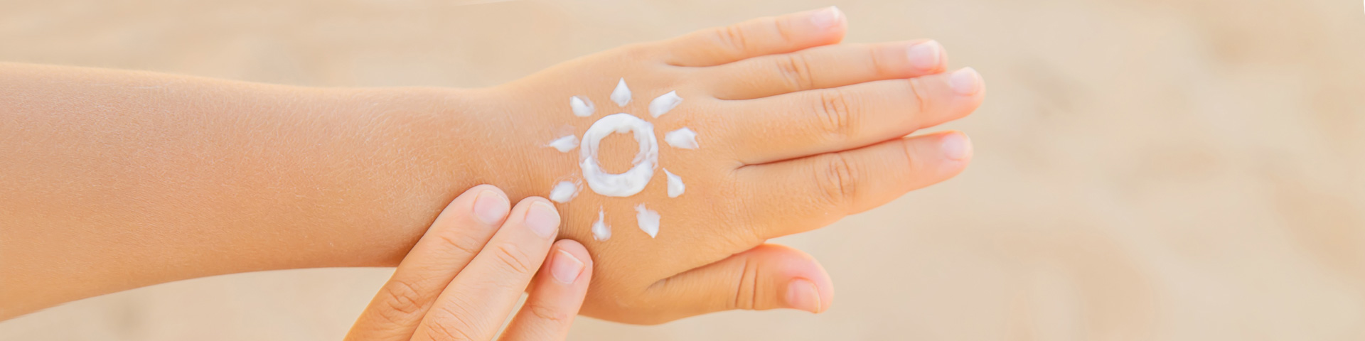Hand mit einem Sonnensymbol aus weißer Creme am Handrücken